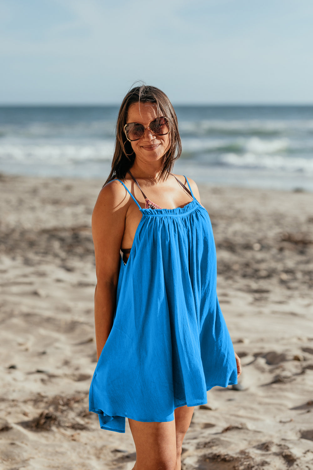 Woman at the beach smiling, wearing Bette Amalie mini cover up in Ocean blue