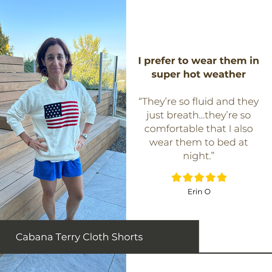 Woman wearing a white sweatshirt with an American flag and blue shorts, standing outdoors.
