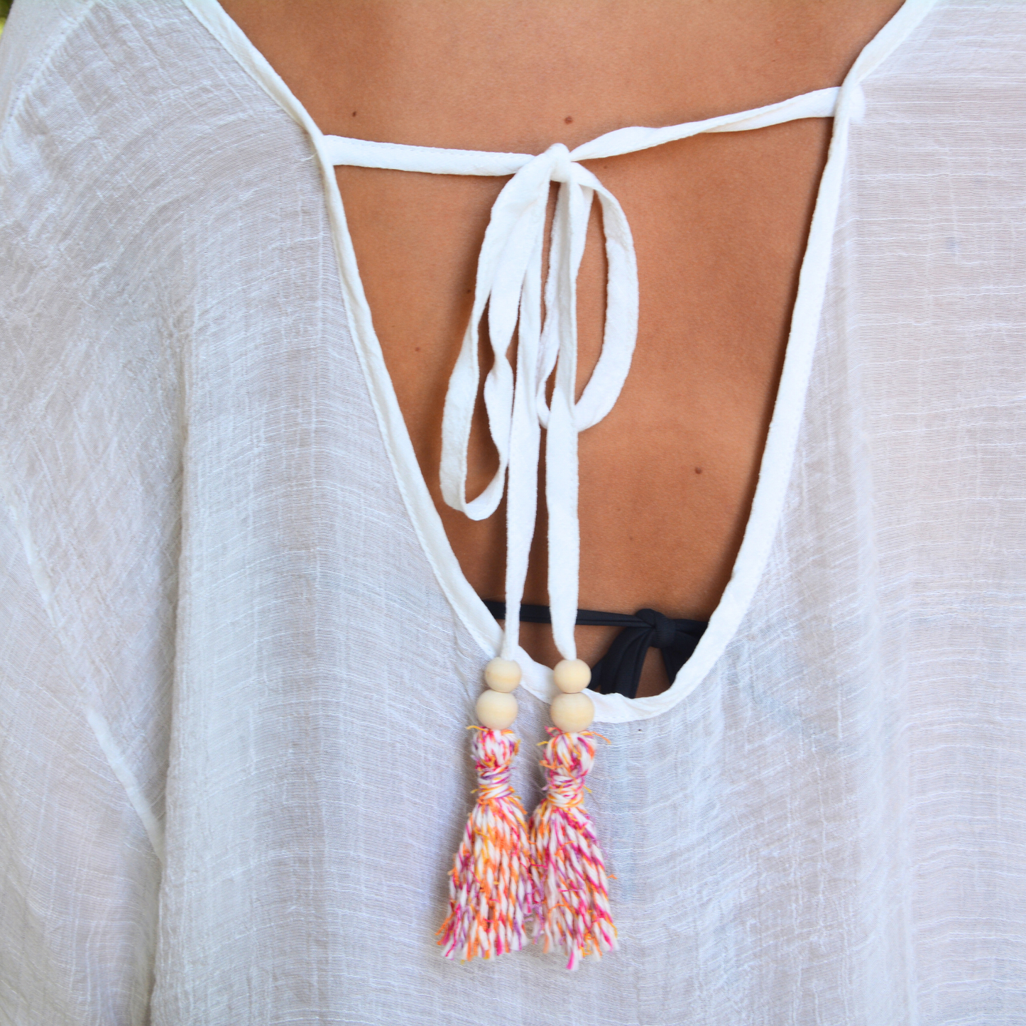 Close up of Bette moorea cover up material in white and orange and pink tassels