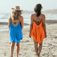 Women walking away from the camera on the beach wearing Bette Amalie mini cover ups in citrus and ocean blue