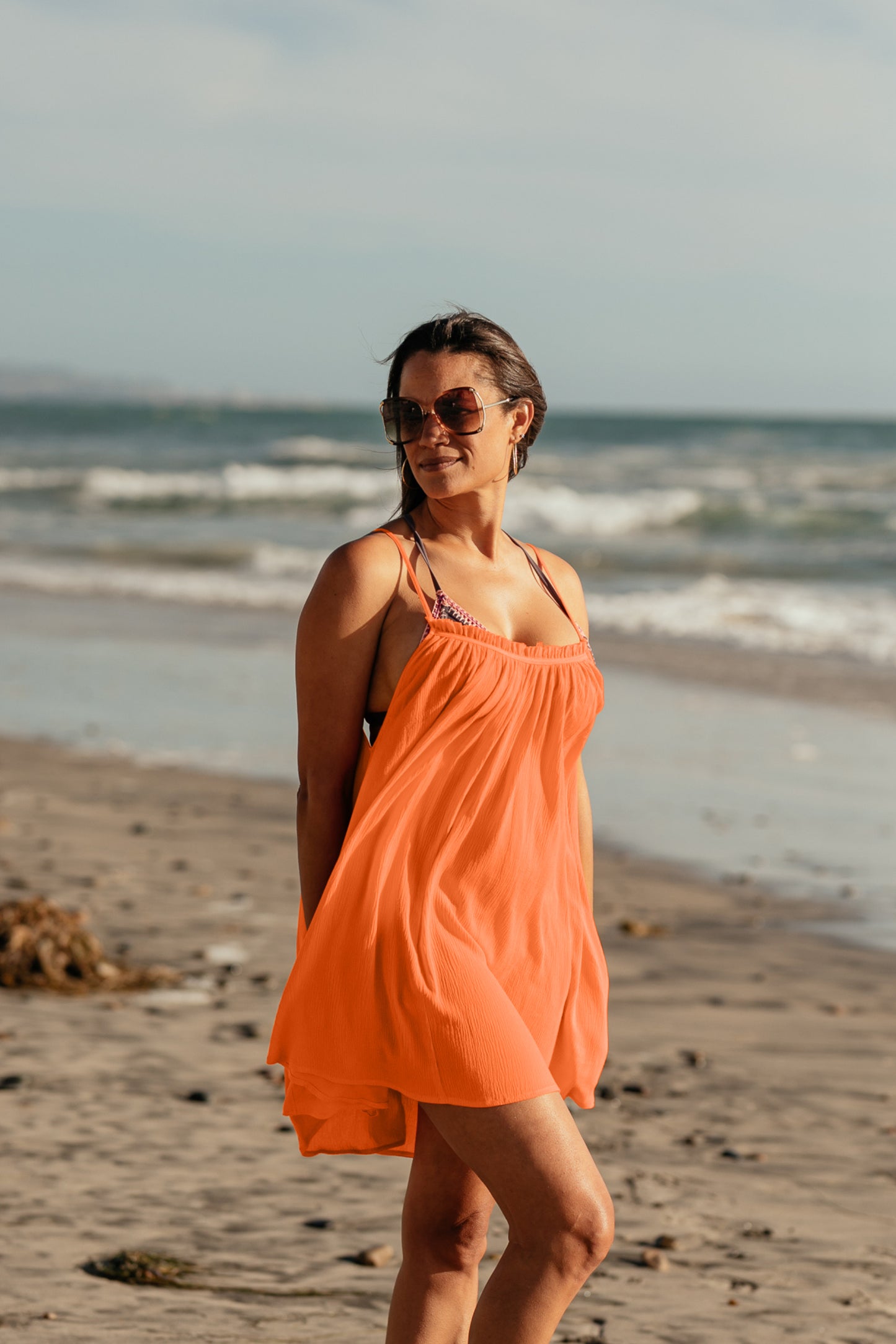 Bette cover up: Woman standing by the ocean wearing Bette's Amalie mini cover up in citrus