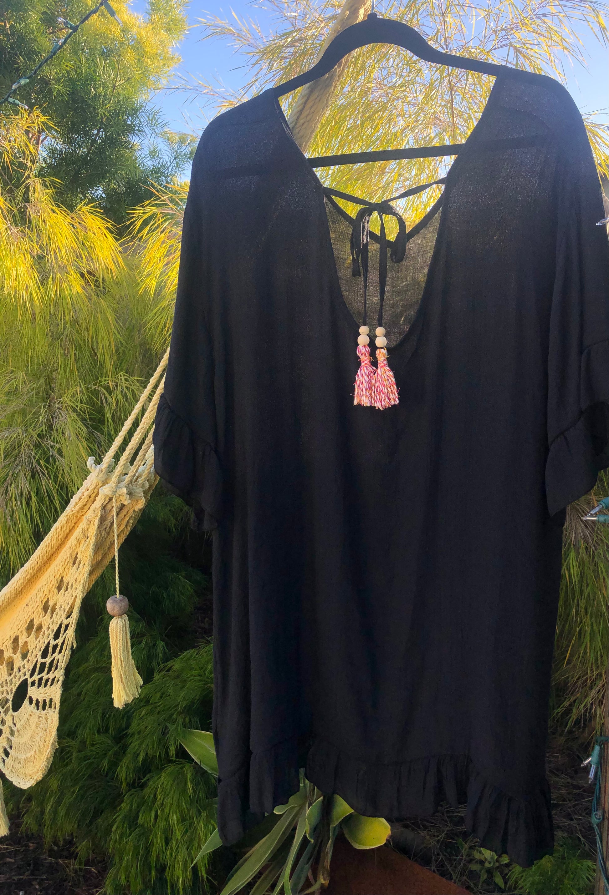 Black dress with pink tassels hanging next to a hammock.