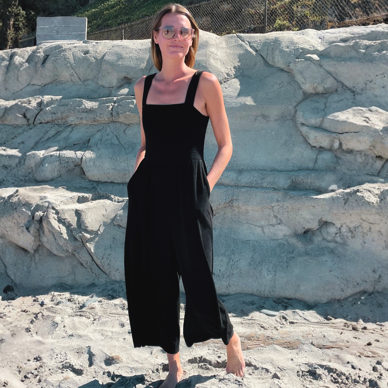 Woman at the beach standing in front of a stone wall.