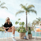 Woman sitting by pool on her phone wearing a black shorts set.