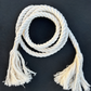 Coiled white rope belt with tassels on a black background