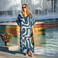 Woman in a blue and white patterned kaftan standing in front of a fountain.