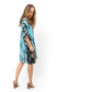 Woman twirling and looking down in a turquoise, black and white short caftan.