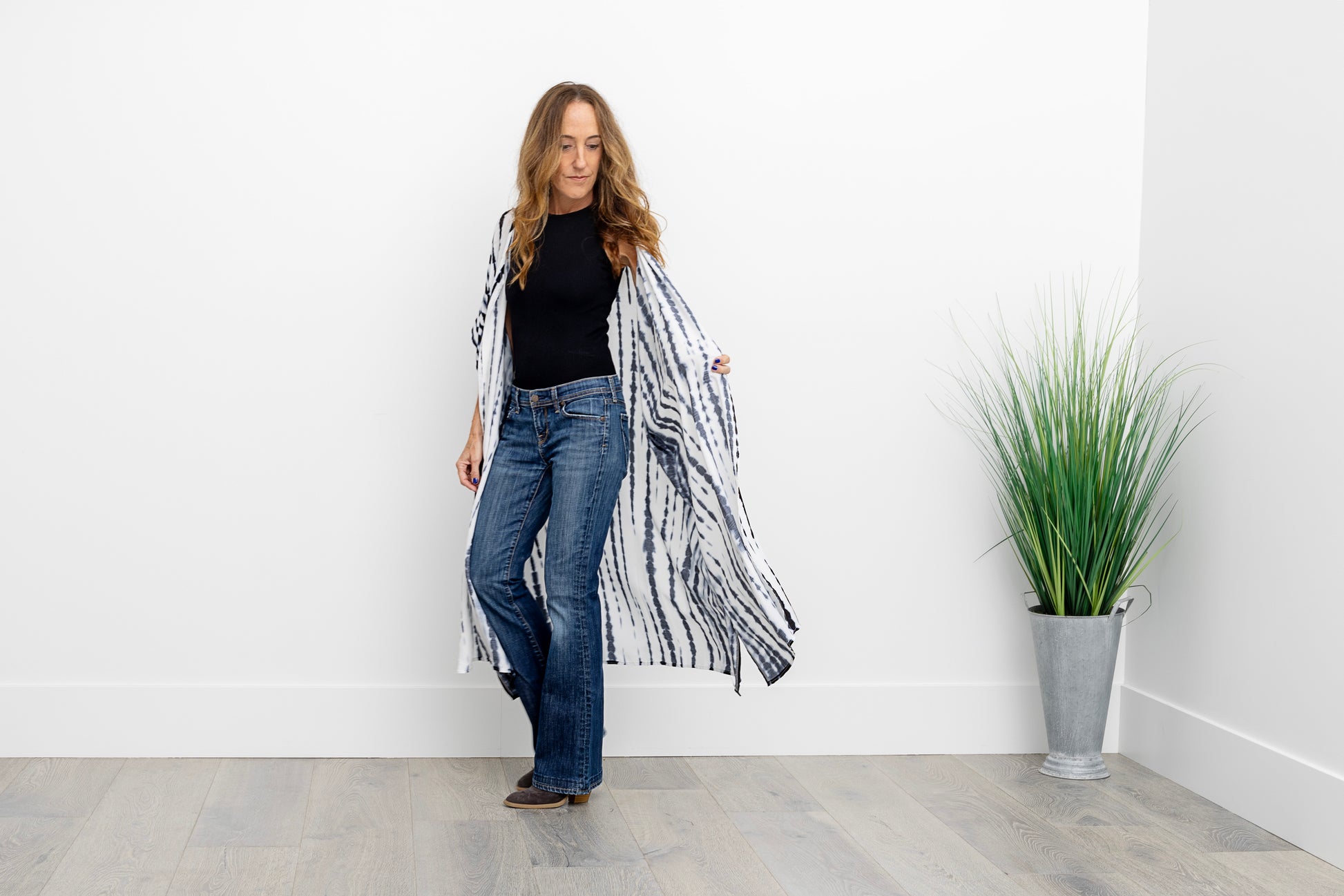 Woman walking in jeans and a long blue and white kimono, opening up the kimono.