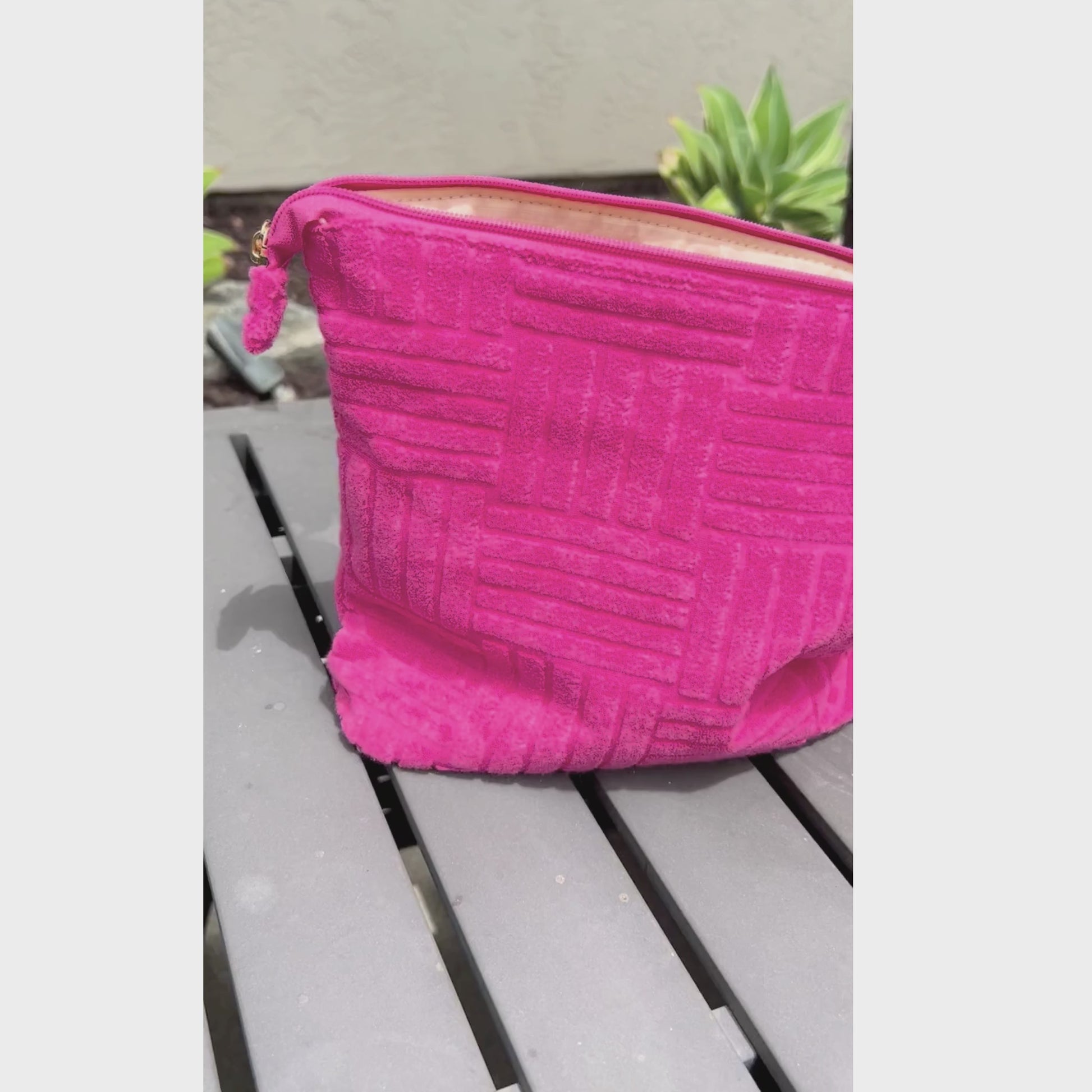 Video of the pink, textured terry cloth outside of a small pouch and the waterproof interior.