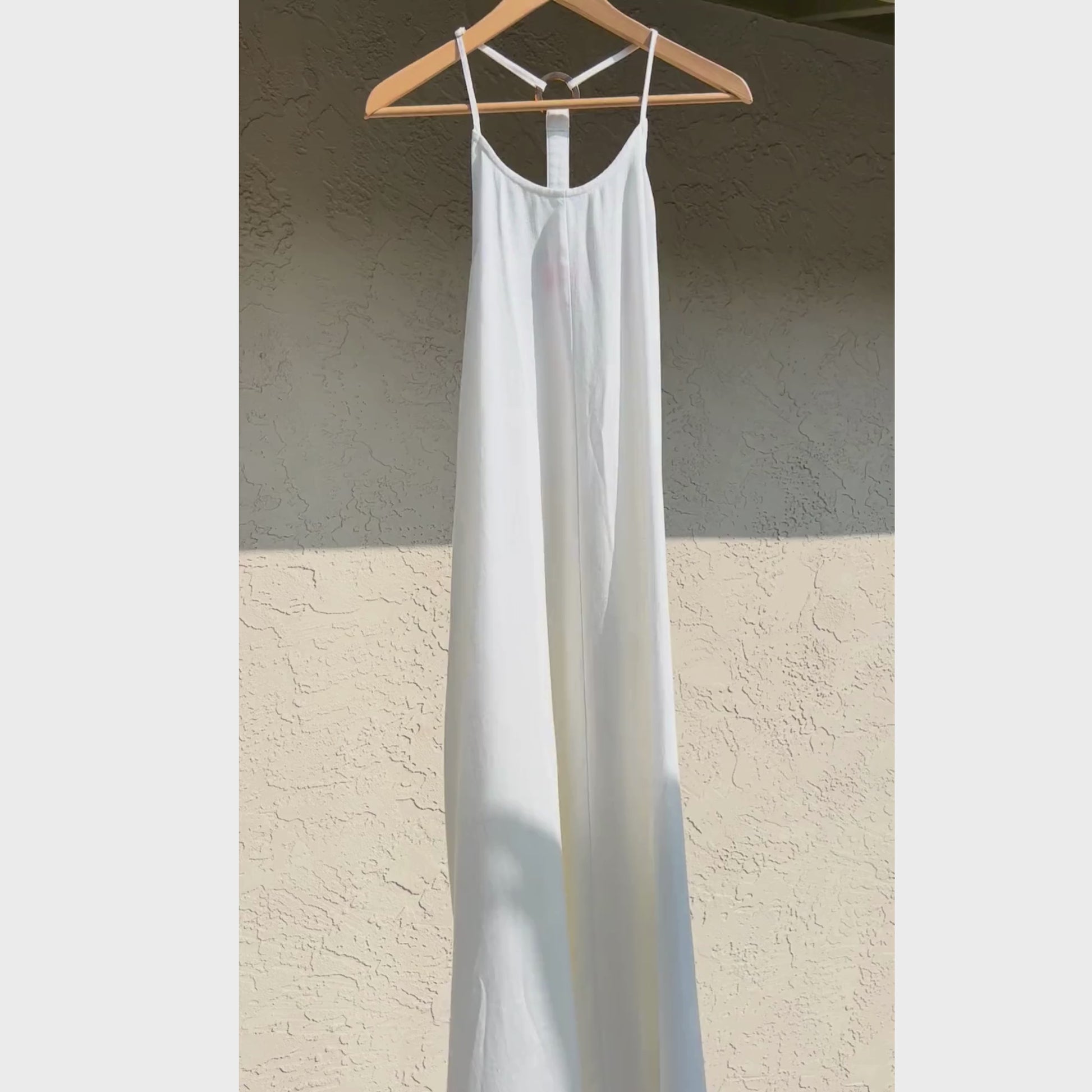 Off white linen dress blowing in the wind on a hanger.