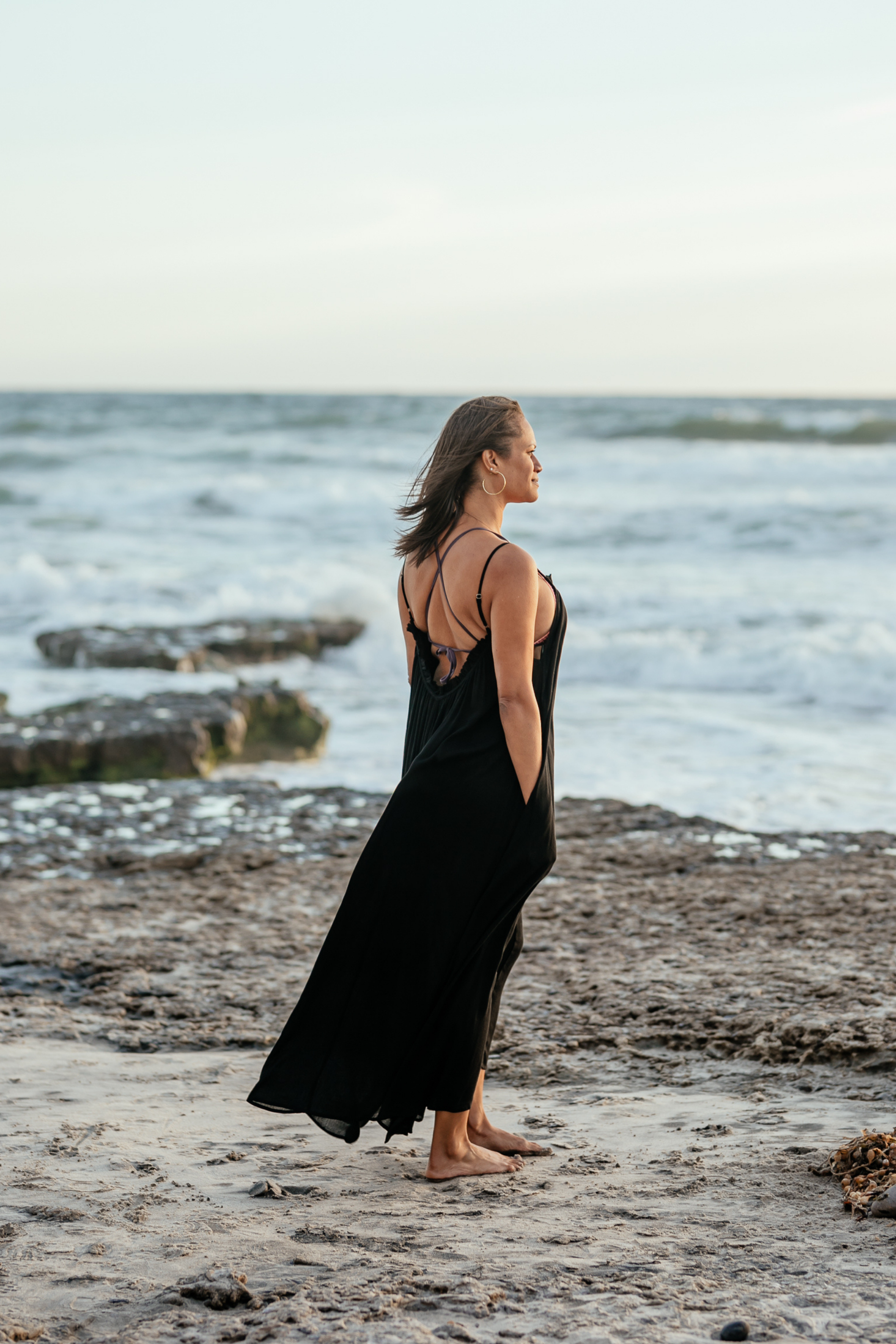 Woman wearing Bette maxi cover up at the beach in California, watching the sun set.