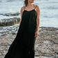 Woman wearing black Bette cover up dress on the beach in the breeze so you can see how fabric flows.