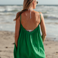 Woman at beach walking away from the camera, looking out at the water as breeze blows her dress.