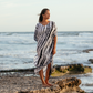 woman standing at low tide looking out at the water. She's wearing a tie dyed, blue and white long caftan dress.